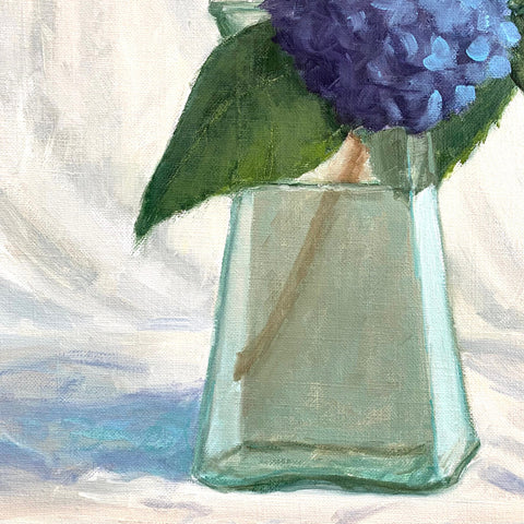 Detail of vase and flowers in still life painting of a vase of blue hydrangeas on a tabletop with white cloth background by Kathy Chumley at Cottage Curator - Sperryville VA Art Gallery