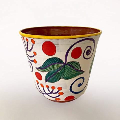 Ceramic vessel with clay red interior and white exterior decorated with bold green, blue, purple and orange plant leaves, with red dots surrounding and a yellow rim, by artist Sara Schneidman at Cottage Curator - Sperryville VA Art Gallery