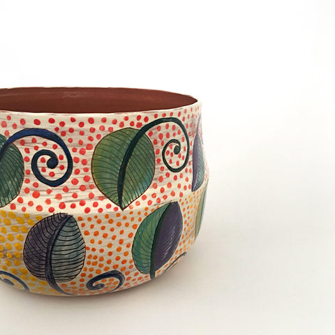 Detail of ceramic bowl with two bands of leaf patterns with red polka dots on the top band and yellow on the bottom band by Sara Schneidman at Cottage Curator - Sperryville VA Art Gallery